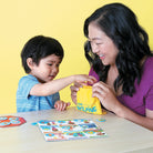 Woman and child playing with a educational game on a yellow background
