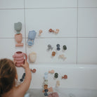Child playing with colorful bath toys on a tiled bathroom wall