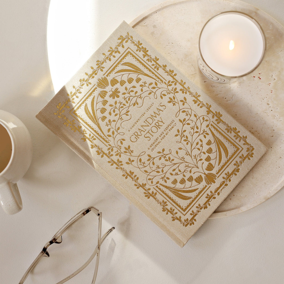 Book titled 'Grandma's Story' with a candle and glasses on a white surface