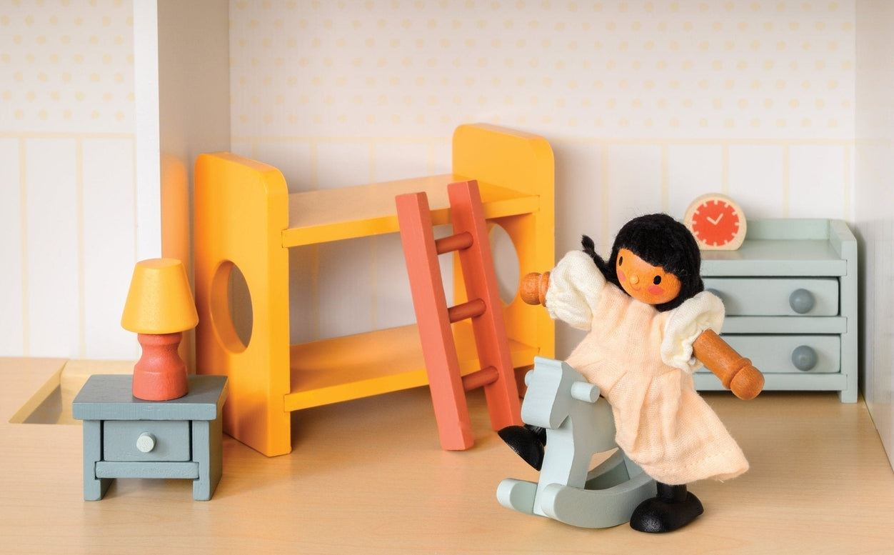 Wooden doll figure riding a light blue rocking horse in a miniature room with a yellow bunk bed, slide, chest of drawers, and bedside table with a lamp.