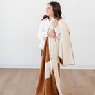 Person holding a brown and beige blanket against a white background