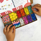 Colorful bead set with hands interacting on a white background