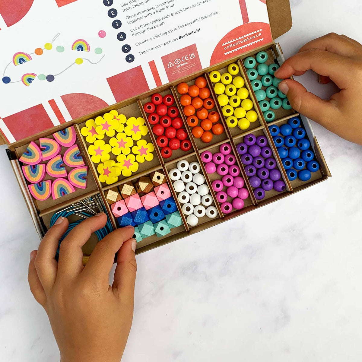 Colorful bead set with hands interacting on a white background