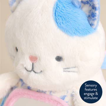 Stuffed animal with blue ears and pink accents on a beige background