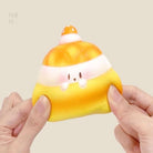 A cute food-themed squishies with a hand holding one, against a light background.