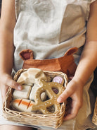 Person holding a basket of soft toys, including a deer-shaped one, with a neutral background.