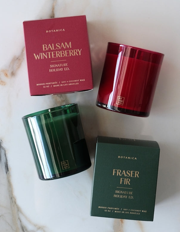 Two candles and their packaging on a marble surface