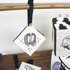 Decorative boxes with black and white designs hanging on a wooden rod.