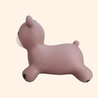 A small, soft silicone bunnie-shaped toy in a dusty mauve-pink color, featuring a white muzzle and small black paw pads, shown against a solid pale beige background.