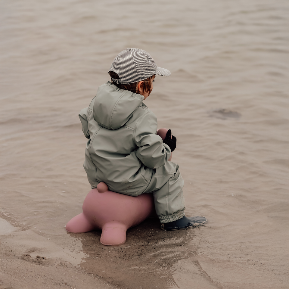 Person sitting on a pink object in a sandy area
