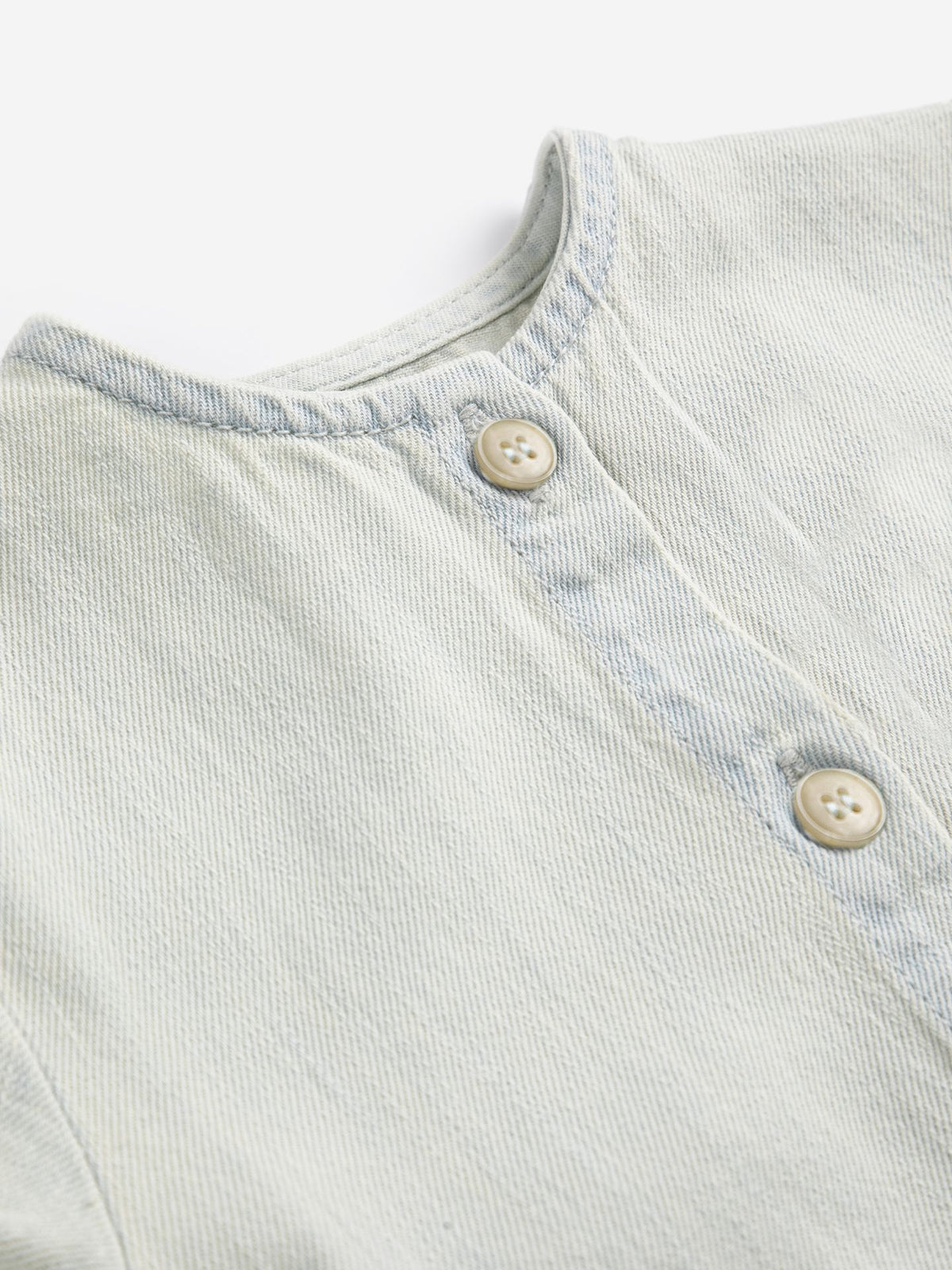 Light blue denim fabric with button details on a white background