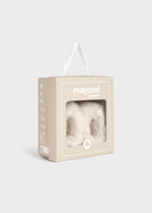 Mayoral Newborn baby booties in a beige presentation box with a clear window showing the fluffy booties inside, set against a light gray background.