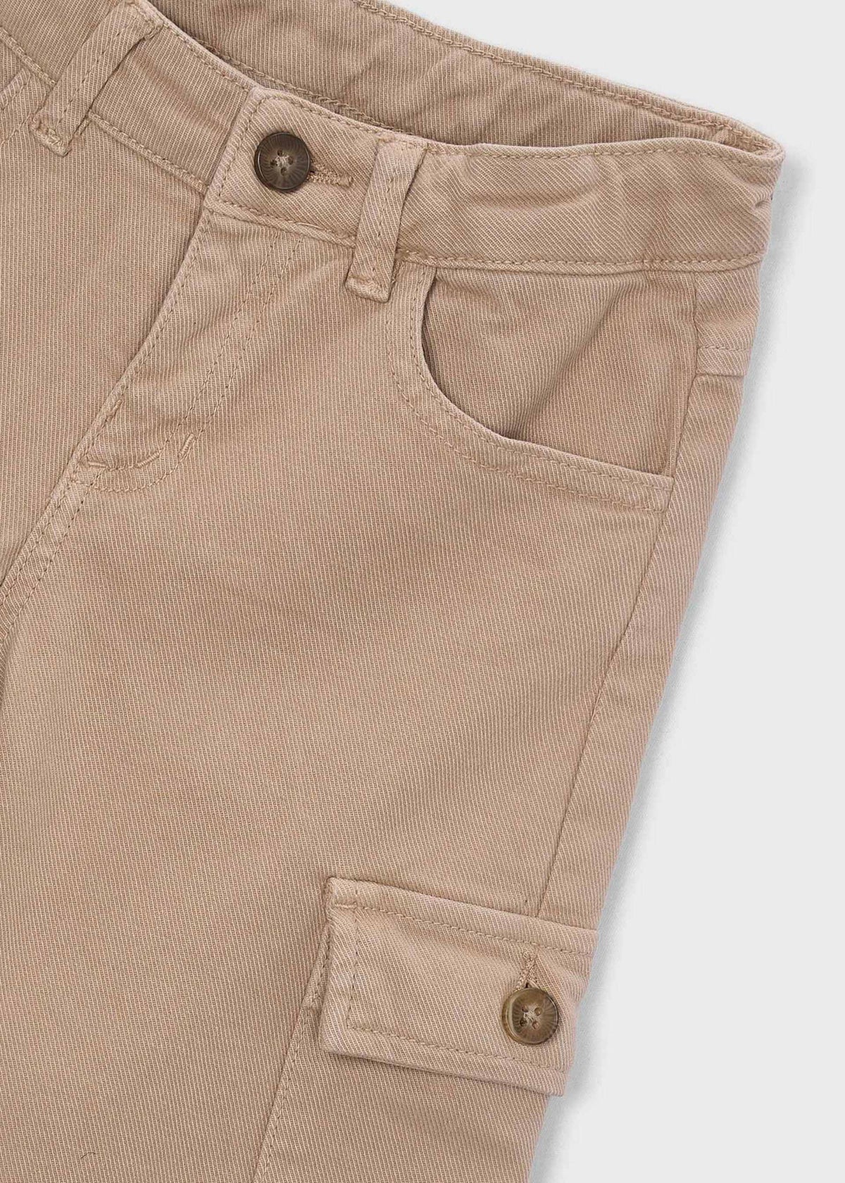 Close-up of beige corduroy pants with button details on a white background