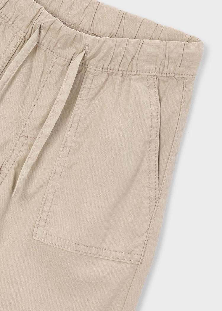 Close-up of beige shorts with a pocket on a light gray background