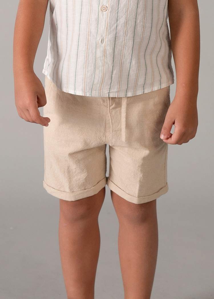 Child wearing beige shorts and a striped shirt on a plain background