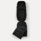 Black backpack with a folded black sleeping pad on a white background
