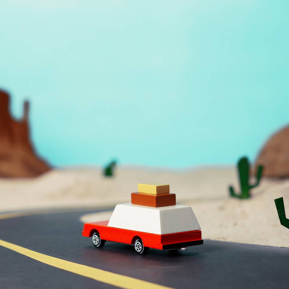 Toy car with boxes on a desert road with cacti and mountains in the background
