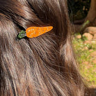 Carrot-shaped hair clip on a person's hair with a natural outdoor background