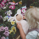 Child holding a plush toy among flowers