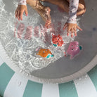 Children playing with colorful rubber ducks in a small pool.