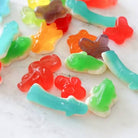 Colorful gummy candy shaped like leaves and flowers on a white surface