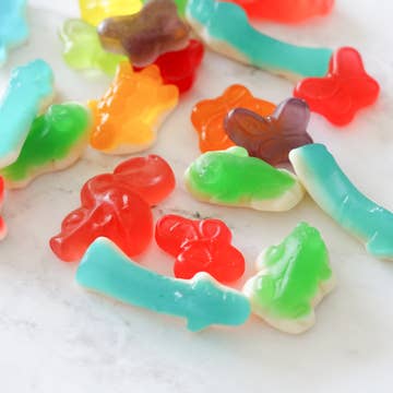 Colorful gummy candy shaped like leaves and flowers on a white surface