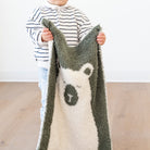 Child holding a soft, plush blanket with a bear design against a plain background