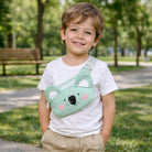 Child wearing a green koala-shaped bag in a park