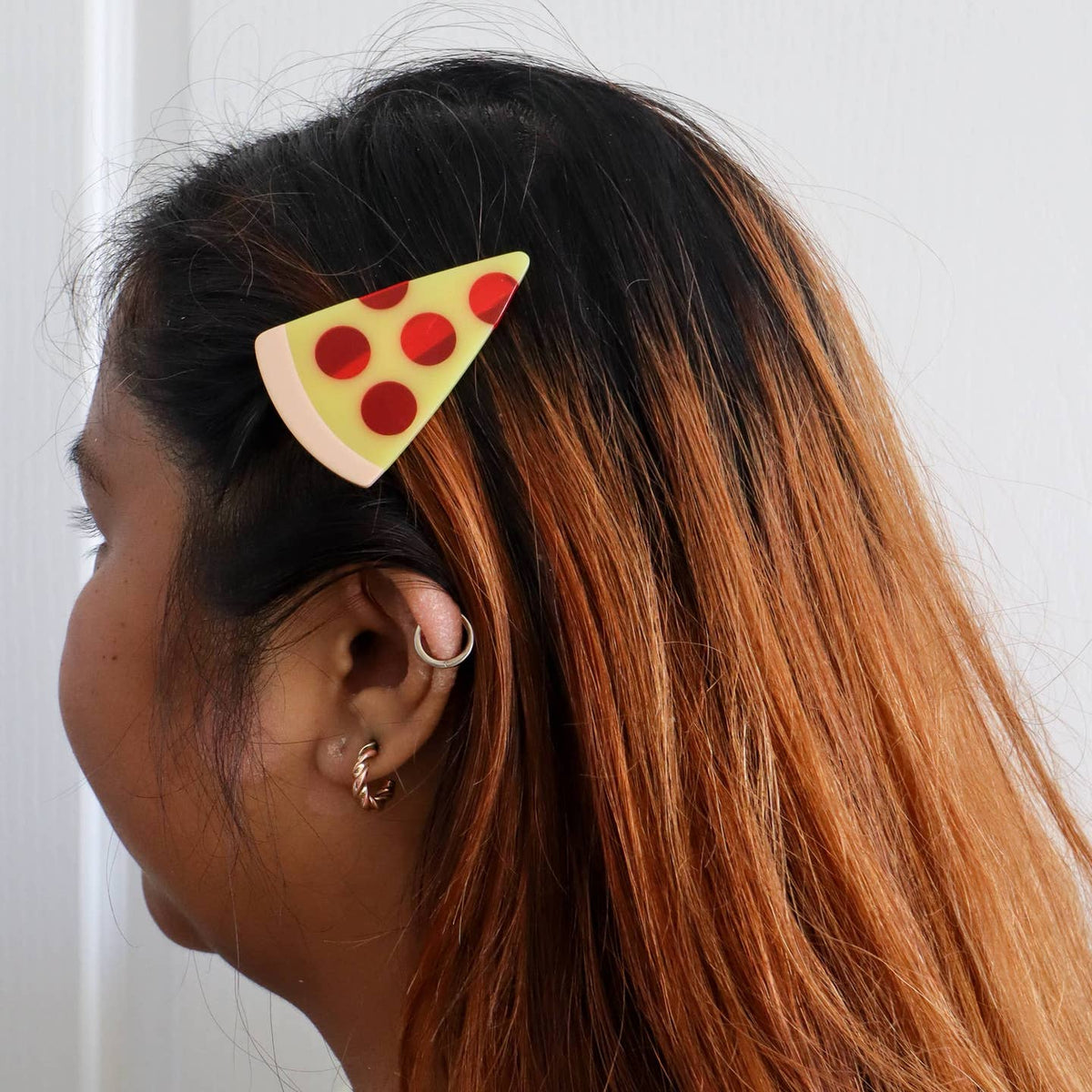 Person wearing a pizza-shaped hair clip on a white background