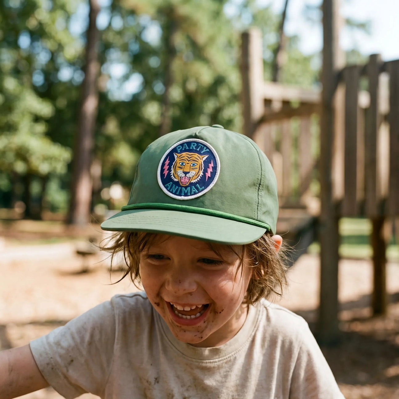 Child wearing a green cap with a tiger emblem in an outdoor setting