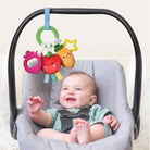 Baby sitting in a gray baby seat with colorful toy hanging above