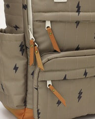 Close-up of a beige backpack with a repeating black lightning bolt pattern, featuring tan leather zipper pulls and a matching beige side pocket.
