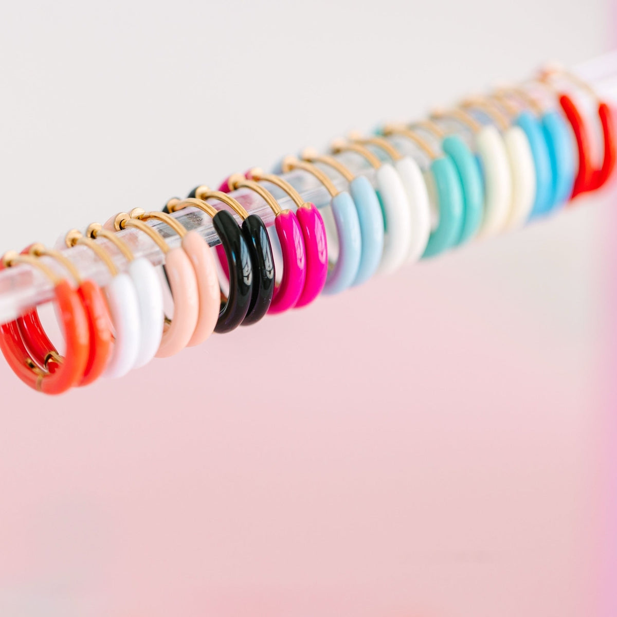 Row of colorful necklaces on a pink surface