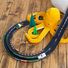 Toy track set with a yellow dinosaur toy on a wooden floor