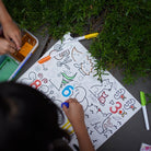 Child coloring a sheet with markers outdoors on grass