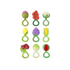 An assortment of nine fruit and vegetable-themed infant rattle and teether toys arranged in a grid, including an artichoke, strawberry, broccoli, pear, grapes, corn on the cob, berries, white gourd, and watermelon slice.