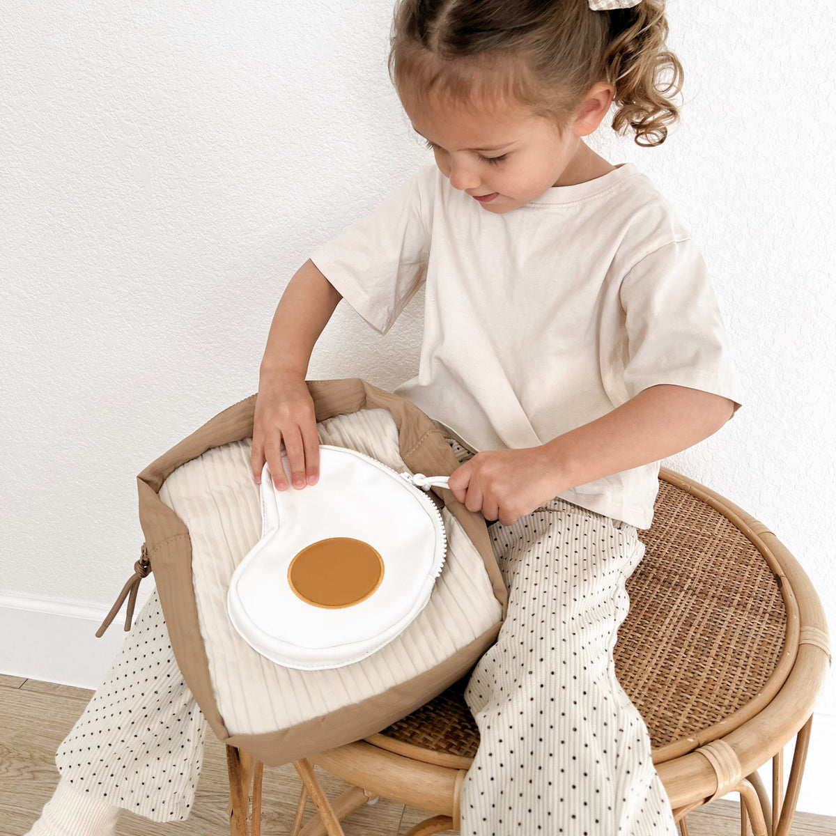 Child playing with a toy kitchen set on a cushioned stool.