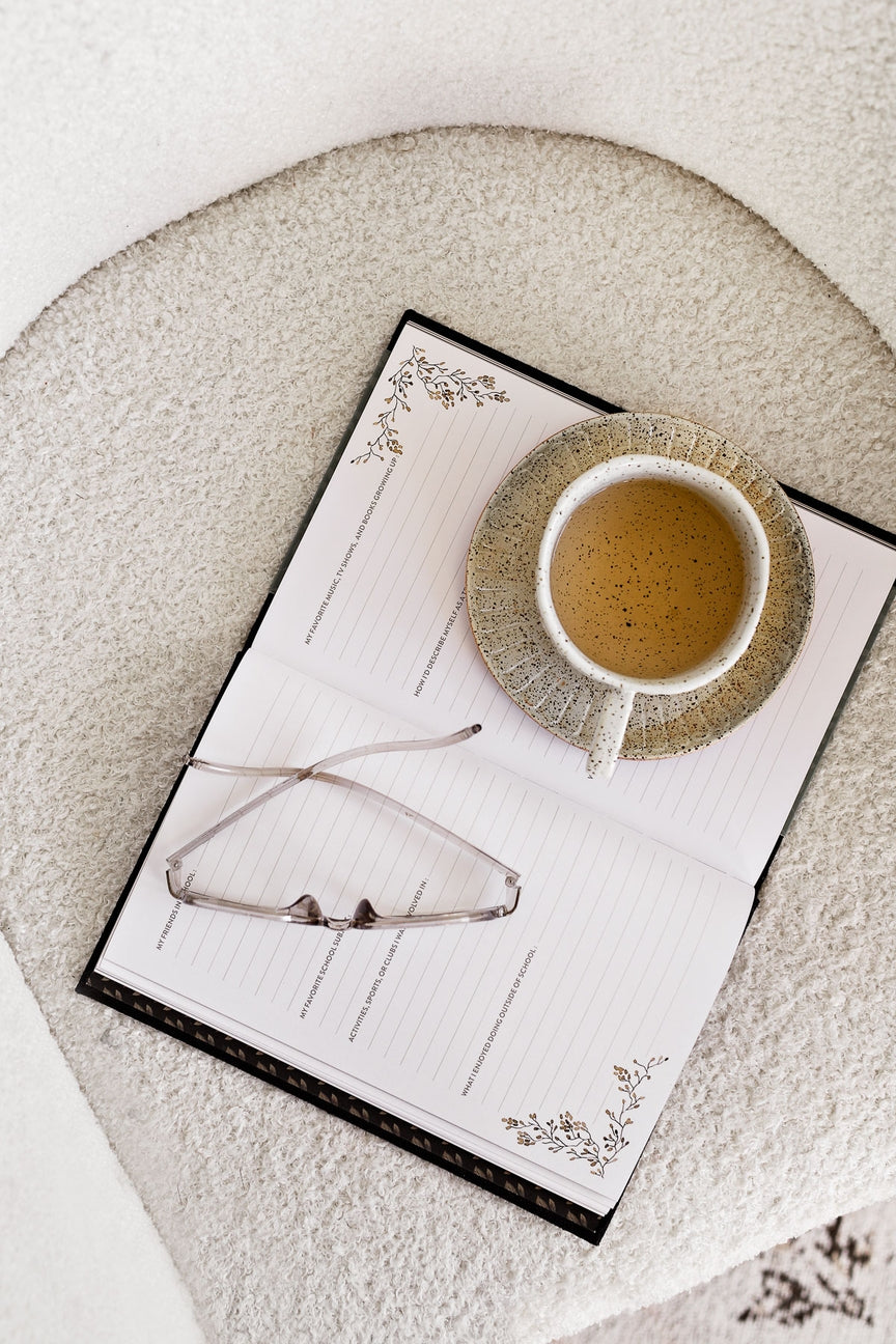 Cup of coffee on a notepad with glasses on a textured surface