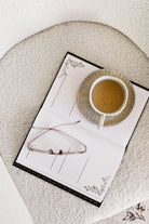 Cup of coffee on a notepad with glasses on a textured surface