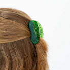Green hair clip on a person's hair against a white background