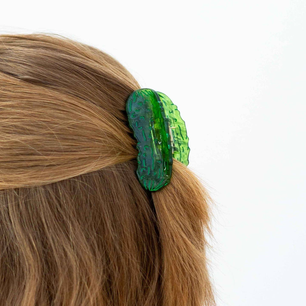 Green hair clip on a person's hair against a white background