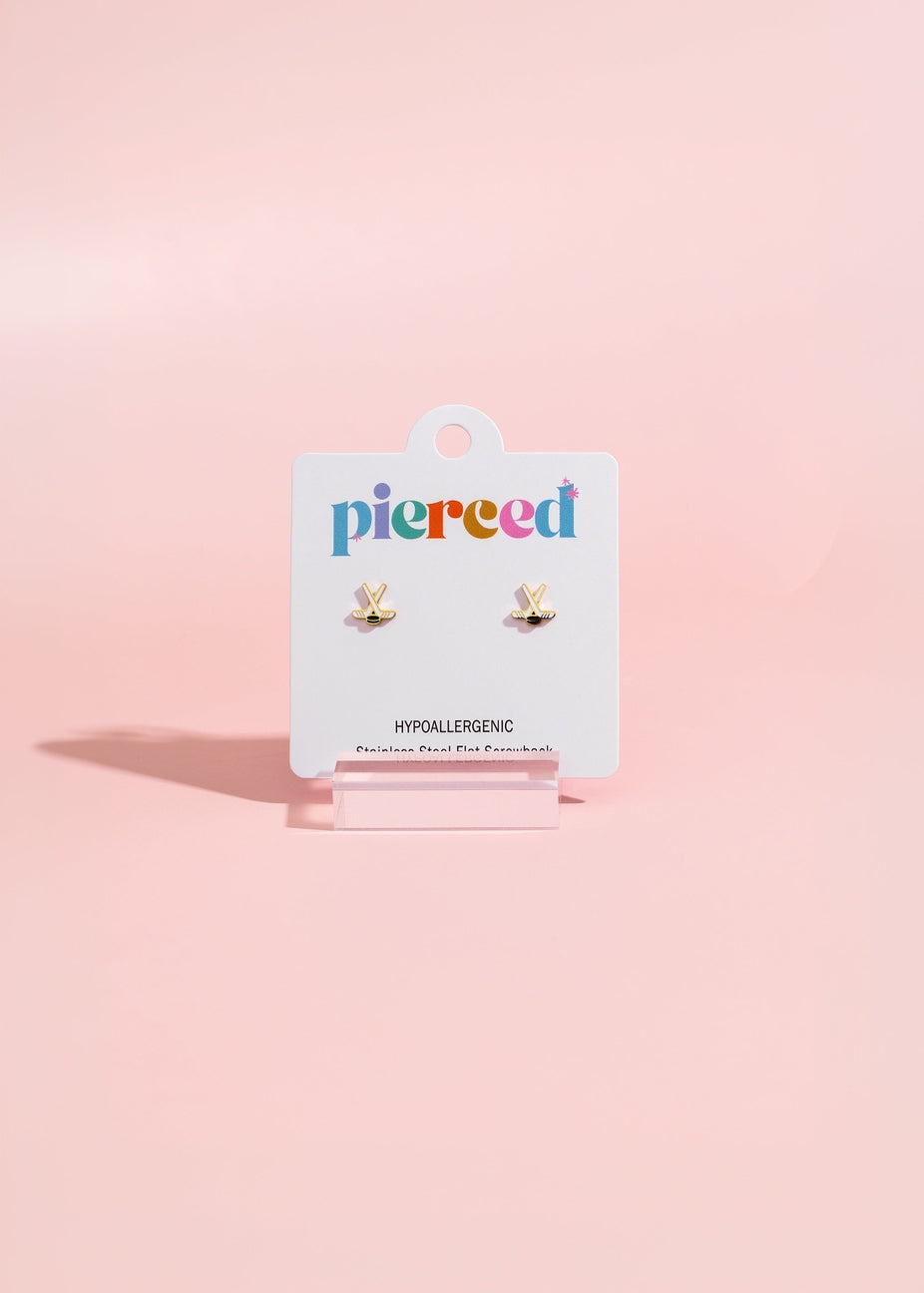 Pair of gold earrings on a 'pierced' branded card against a pink background
