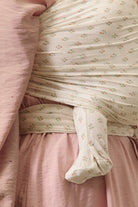 Close-up of a baby in a floral outfit wrapped in a pink blanket