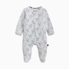 A baby footed sleeper in white with a repeating gray crescent moon and star pattern, featuring a colorful striped inner collar and a small red tag near the ankle.