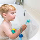 Child playing with a toy in a bathtub using a suction cup attachment.