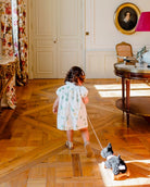 Child in a formal setting with a toy on a wooden floor