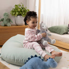 Child sitting on a bean bag with stuffed animals in a cozy room