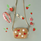 Woven handbag with strawberry and flower decorations on a light gray background