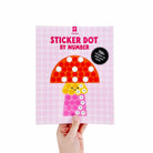 Sticker book titled 'Sticker Dot by Number' held by a hand on a white background.