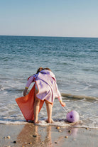 Person with a pink towel and orange skirt playing in the ocean.